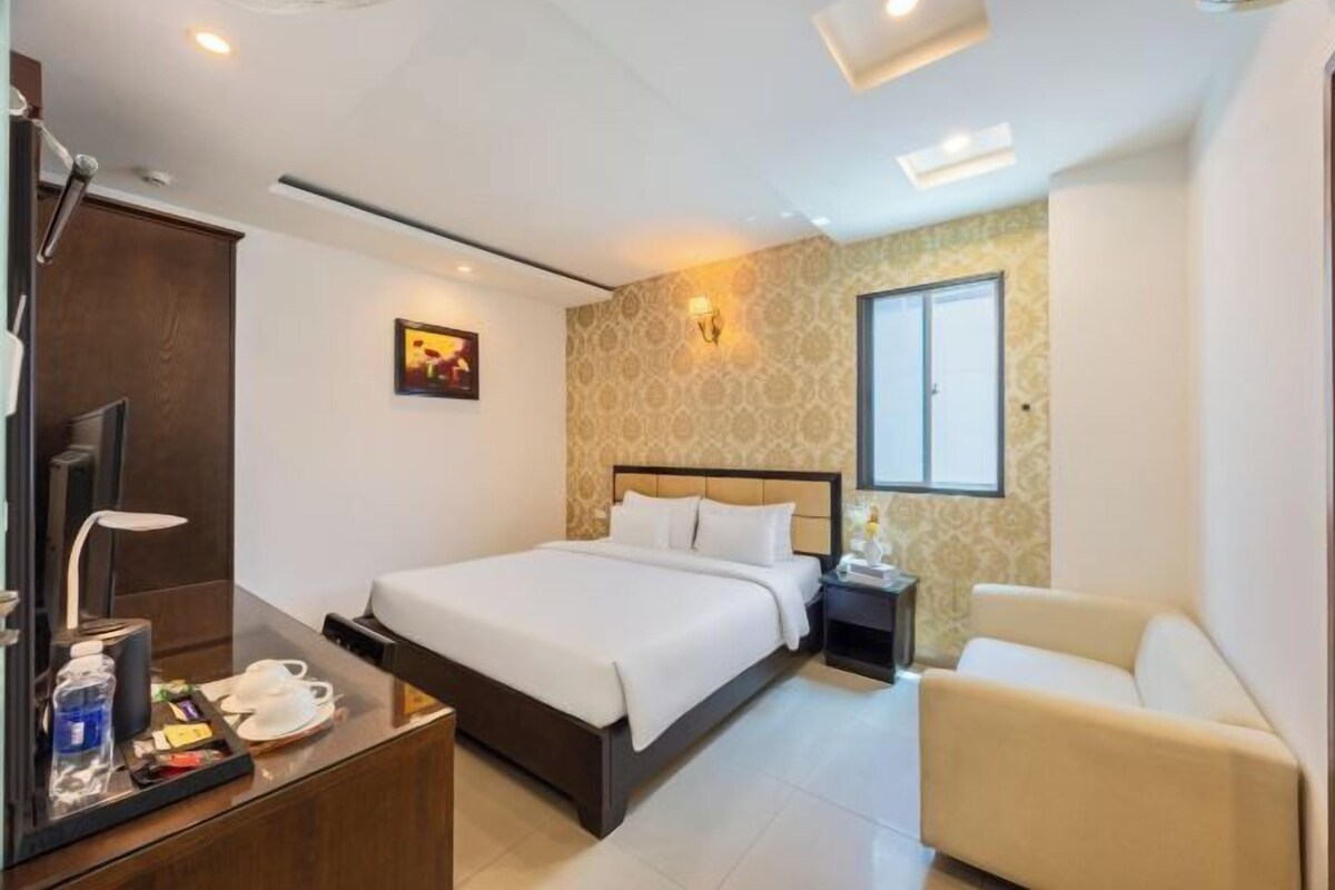 Ein Hotelzimmer mit Bett, Nachttisch, Lampe und einer kleinen Sitzecke.