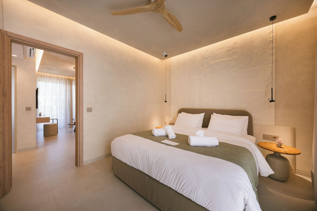 A modern hotel room with a large bed, a ceiling fan, and a bedside table with a lamp.