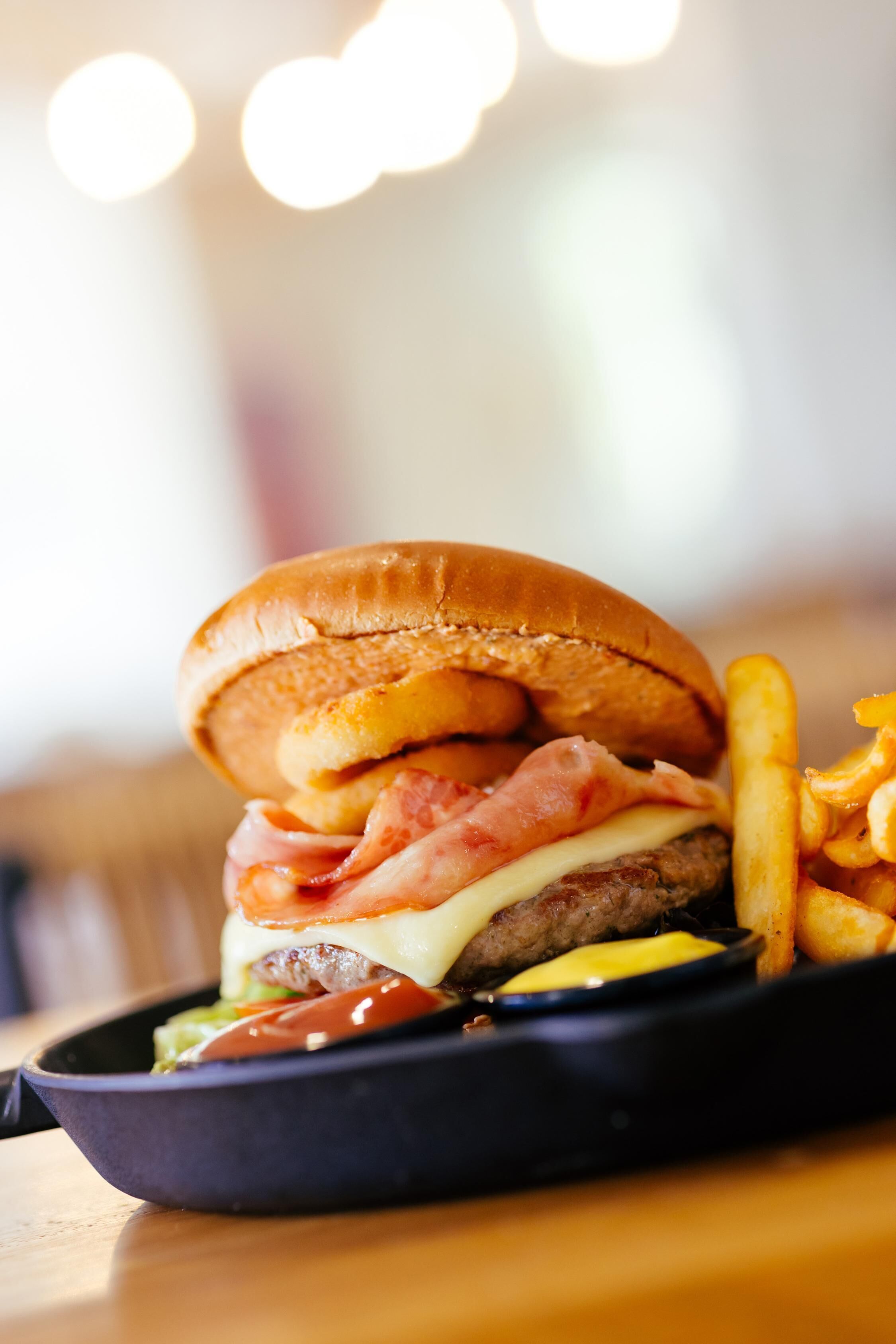 A burger with fries on a black plate.