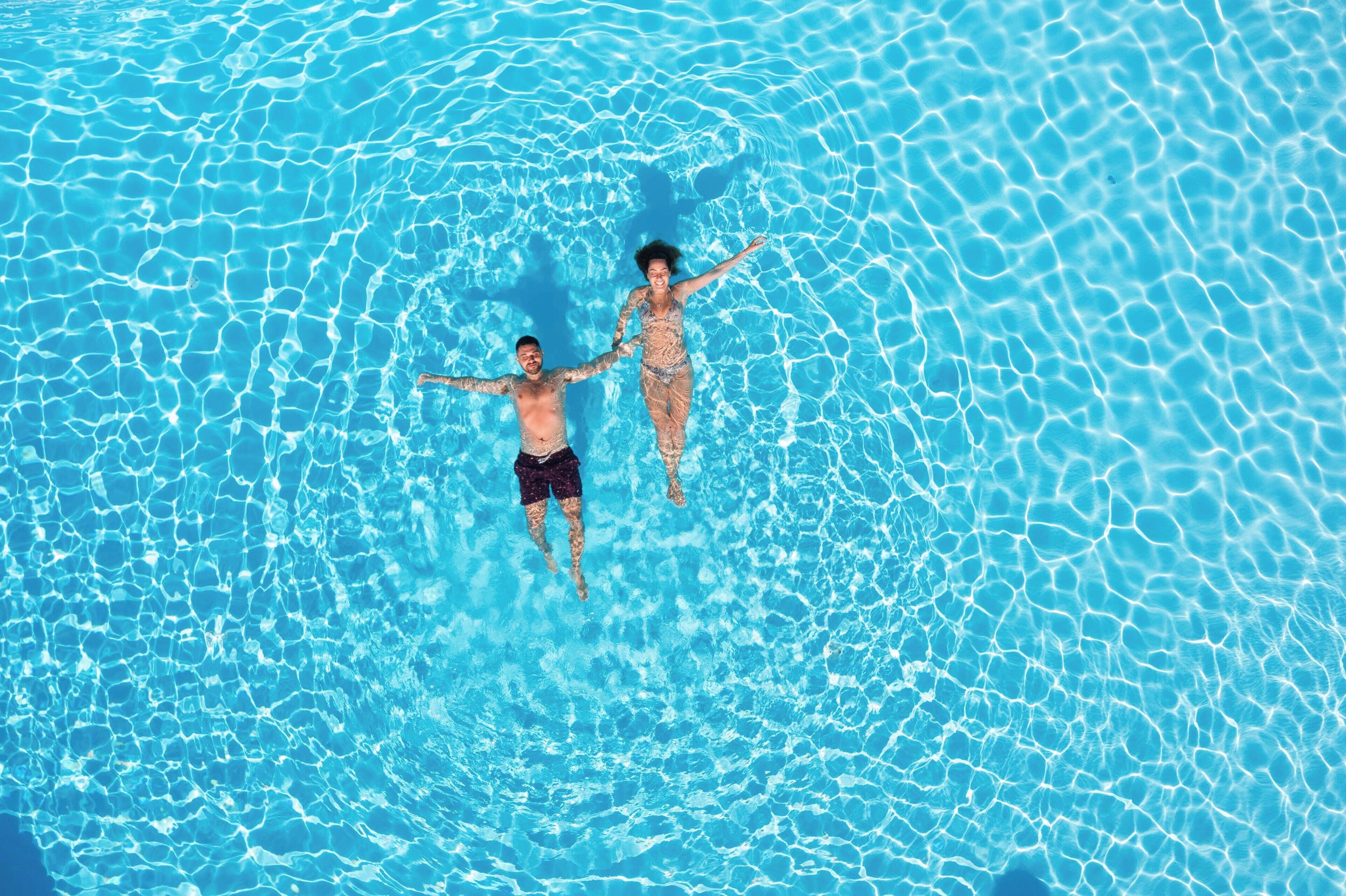 Vista aérea de una piscina con dos personas flotando.