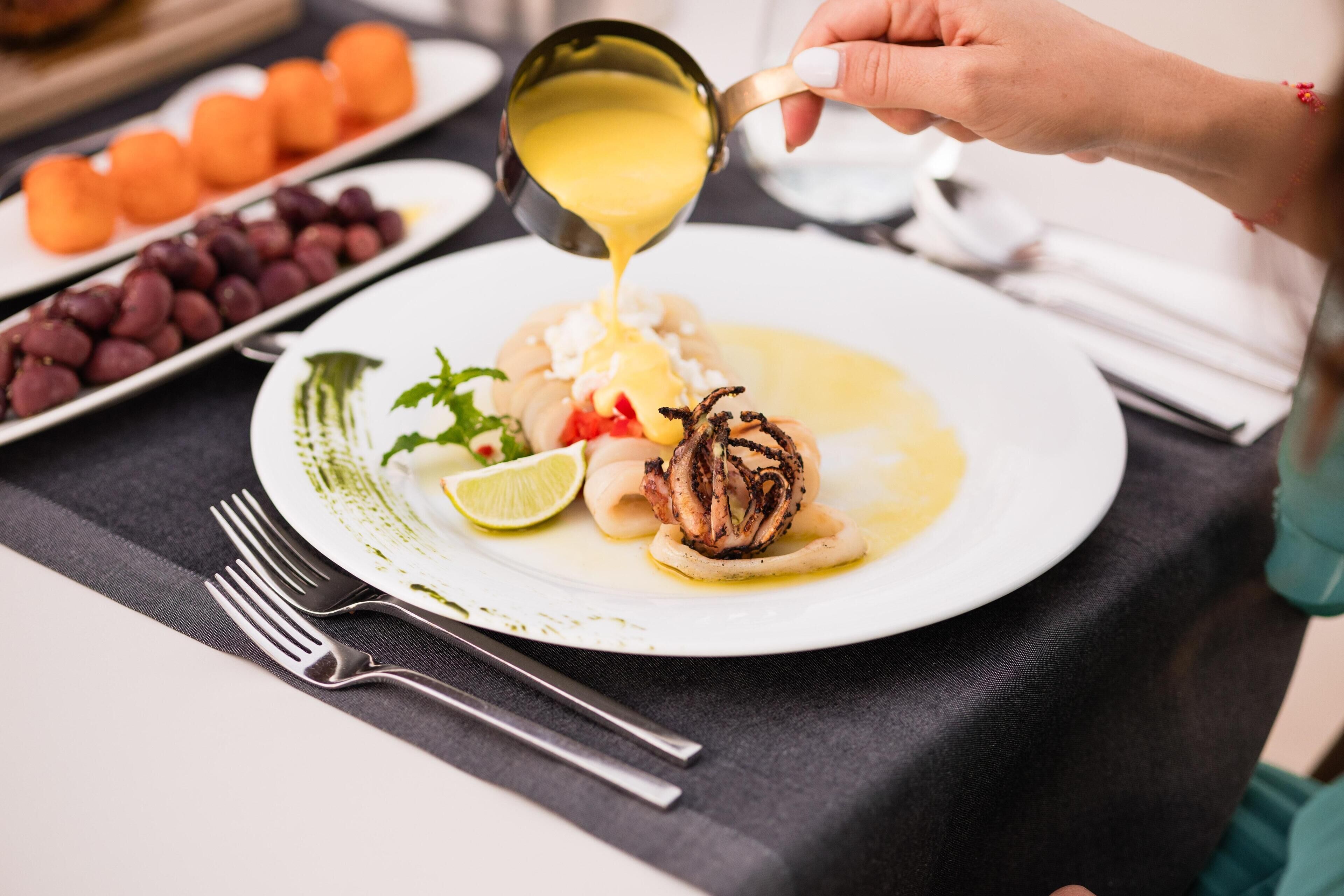 A person pouring sauce onto a plate of food.