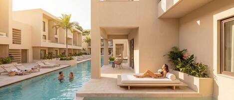 A modern resort with a swimming pool, lounge chairs, and a couple relaxing by the pool.