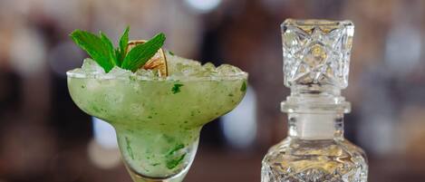 A cocktail glass with a lime wedge and mint garnish on a bar counter.