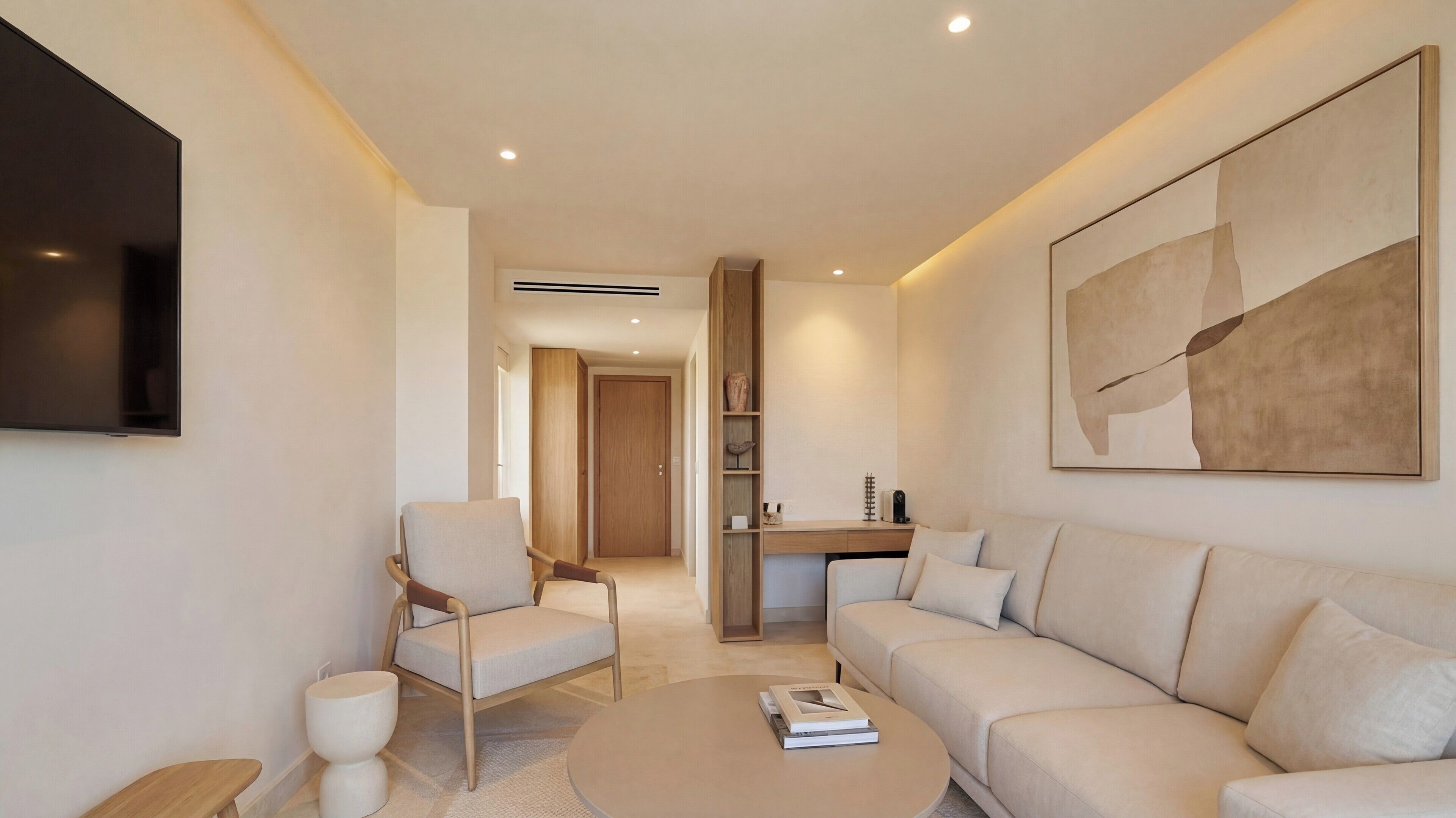 Un salon moderne avec un canapé, des fauteuils, une table basse et un téléviseur.