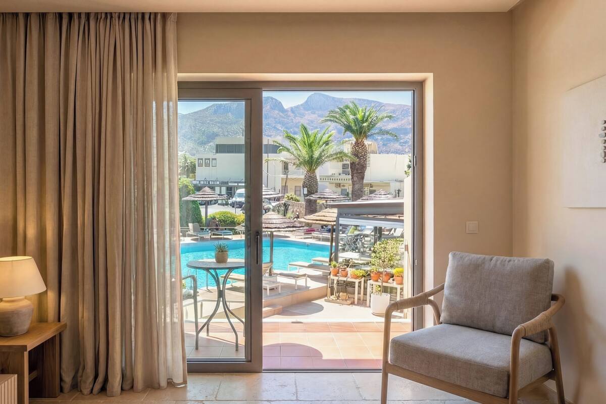 Habitació d'hotel amb vista a una piscina i a les muntanyes.