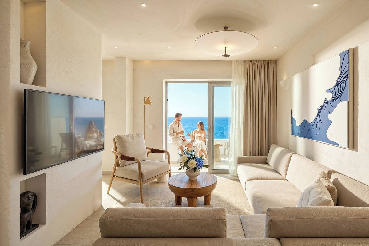 Un saló espaiós amb un gran televisor de pantalla plana, seients confortables i vista a l'oceà a través d'una porta corredissa de vidre.