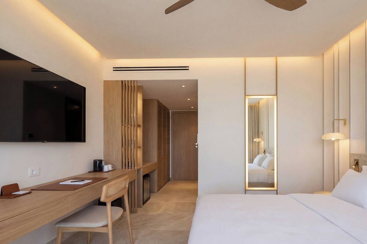 Habitació d'hotel moderna amb llit, escriptori, cadira i un gran mirall.