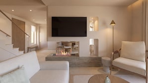 Ein modernes Wohnzimmer mit Flachbildfernseher, Kamin, Sofa, Couchtisch und Stehlampe.