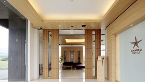 Un hall d’hôtel moderne comprenant un comptoir d’accueil, un espace salon et une grande fenêtre donnant sur l’extérieur.