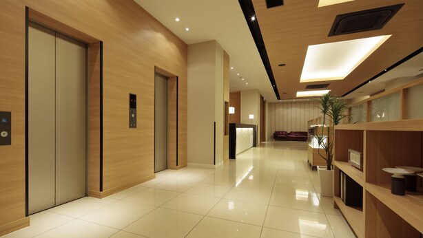 Un hall d'hôtel moderne avec des panneaux de bois, un comptoir d'accueil et un espace de réception.