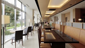 Un espace repas moderne avec de longues tables et des banquettes, de grandes fenêtres offrant une vue sur l’extérieur et un aménagement intérieur épuré et minimaliste.