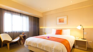 A hotel room with a large bed, a chair, a small table, and a nightstand with a lamp. - Hotel Riverview Taipei (Taipei)