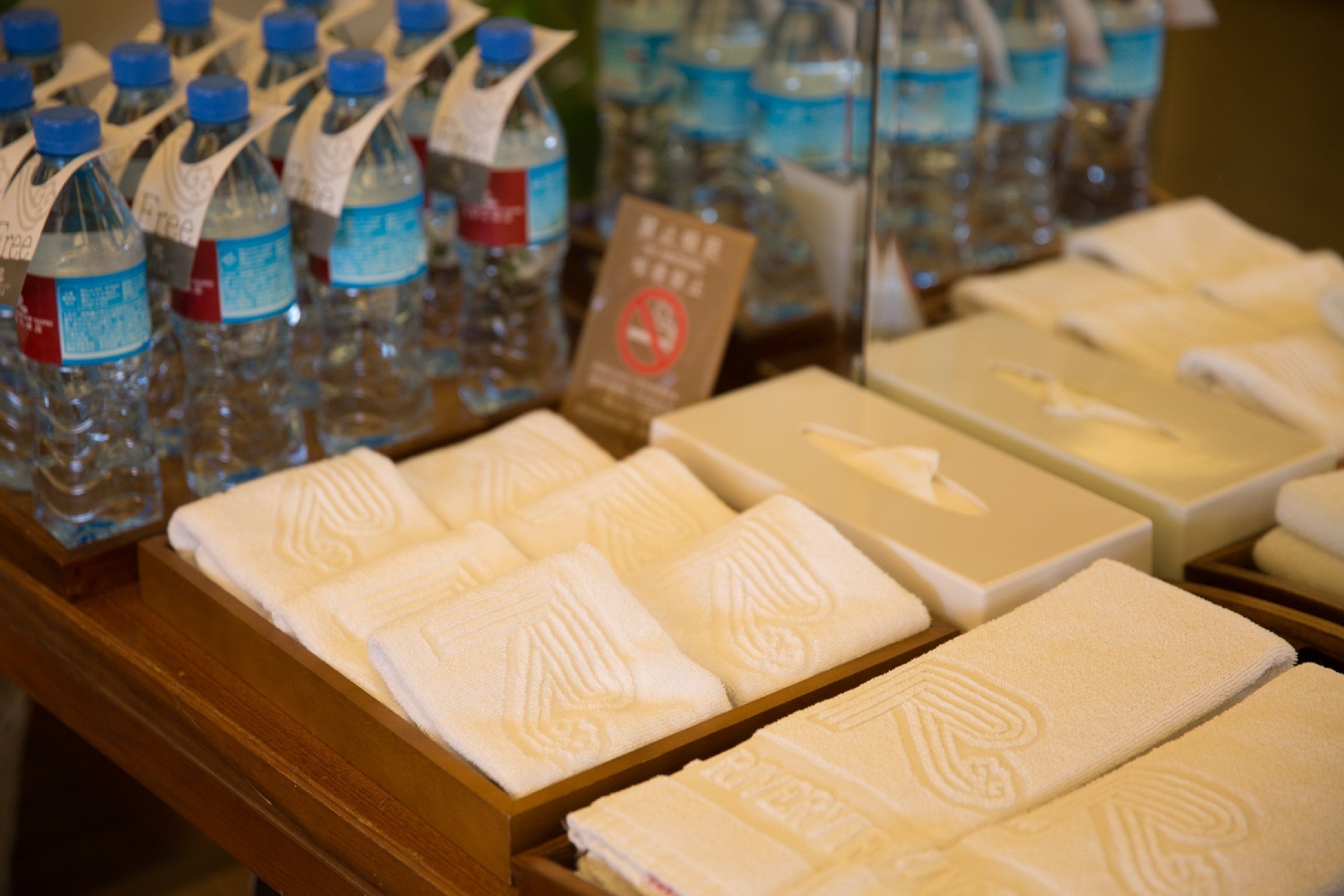 A display of bottled water and neatly folded towels in wooden boxes.