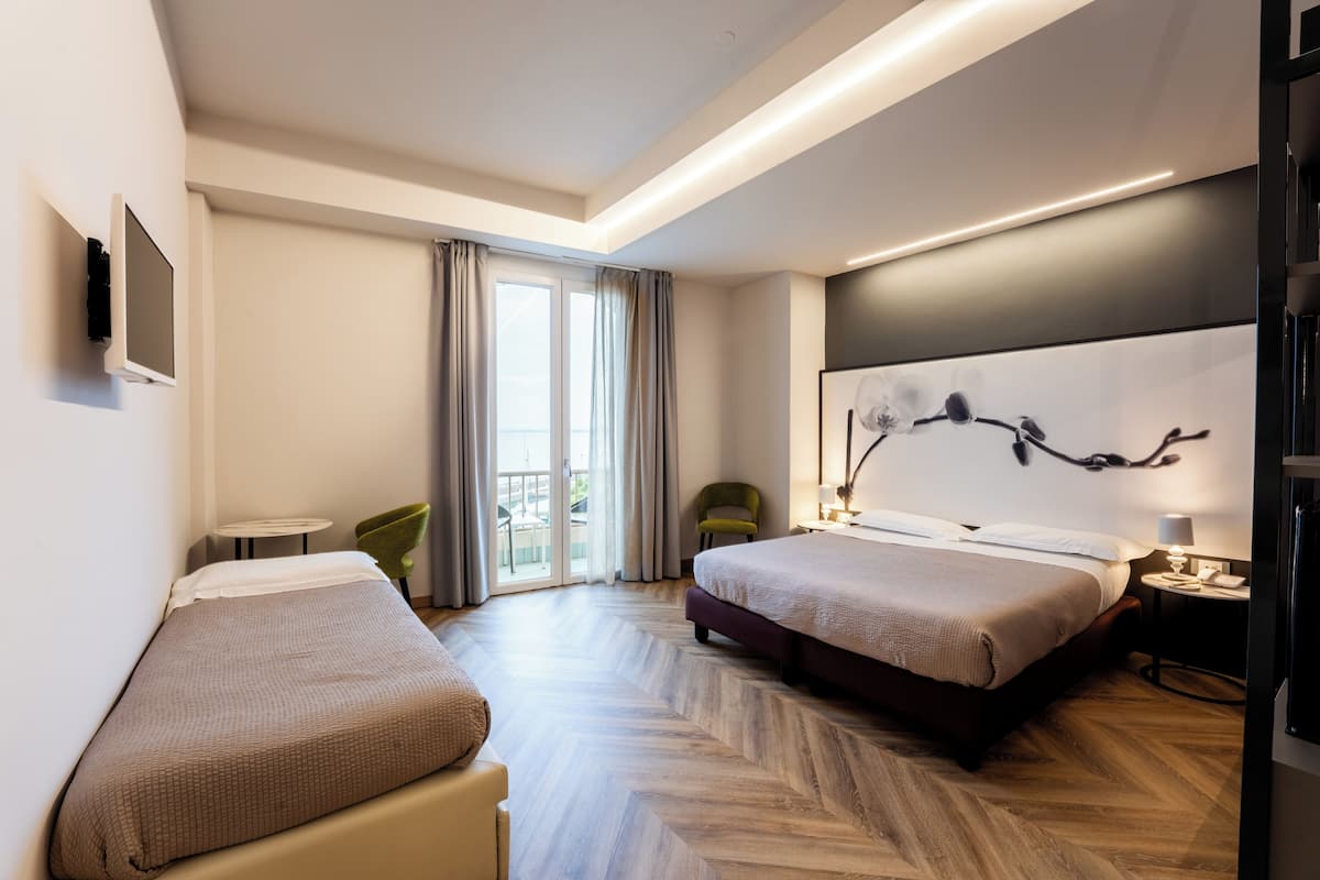 A hotel room with two beds, a TV, a chair, a lamp, and a view of the outdoors.
