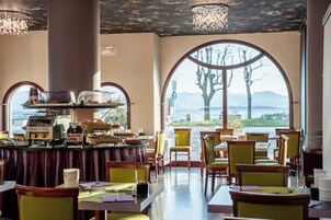 Un restaurant avec vue sur les montagnes, un buffet proposant une variété de plats et une machine à café.