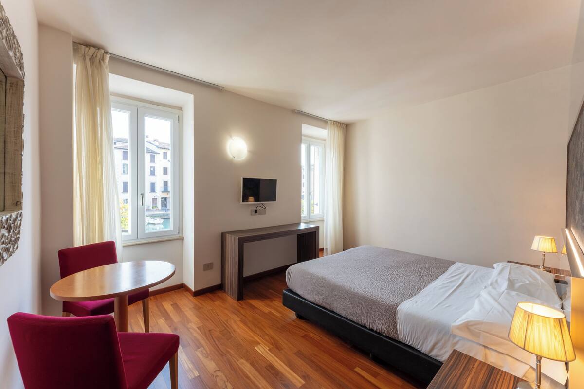 A hotel room with a bed, a desk, a chair, and a TV.