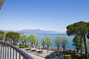 A balcony with a view of a lake, trees, and mountains in the distance.