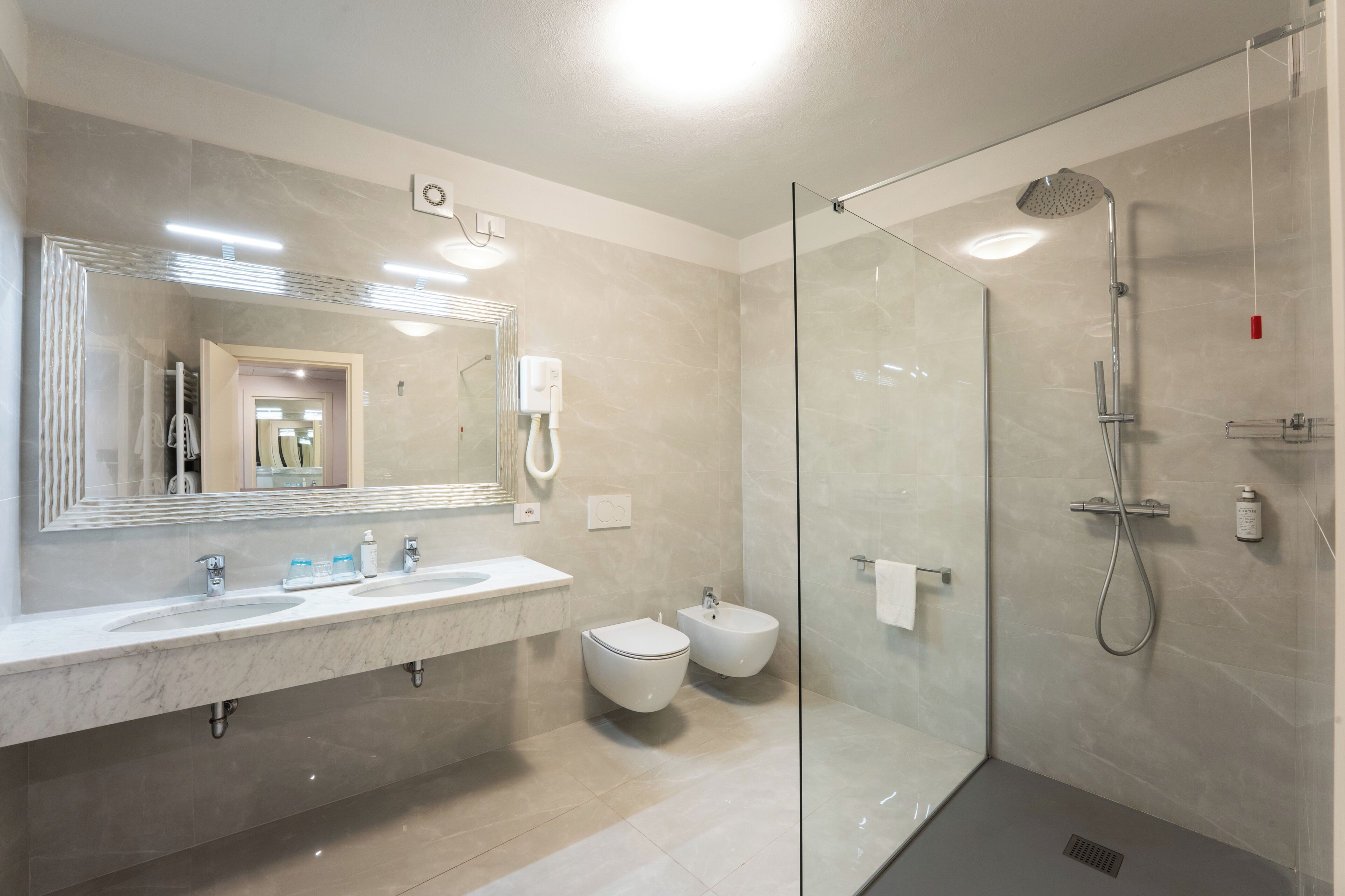 A modern bathroom with a glass shower enclosure, a large mirror, and a dual sink vanity.