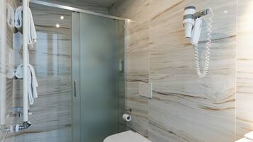 A modern bathroom with a bidet, a glass shower enclosure, and a towel rack.