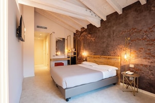 A bedroom with a bed, a bedside table, a mirror, and a wall with a textured pattern.