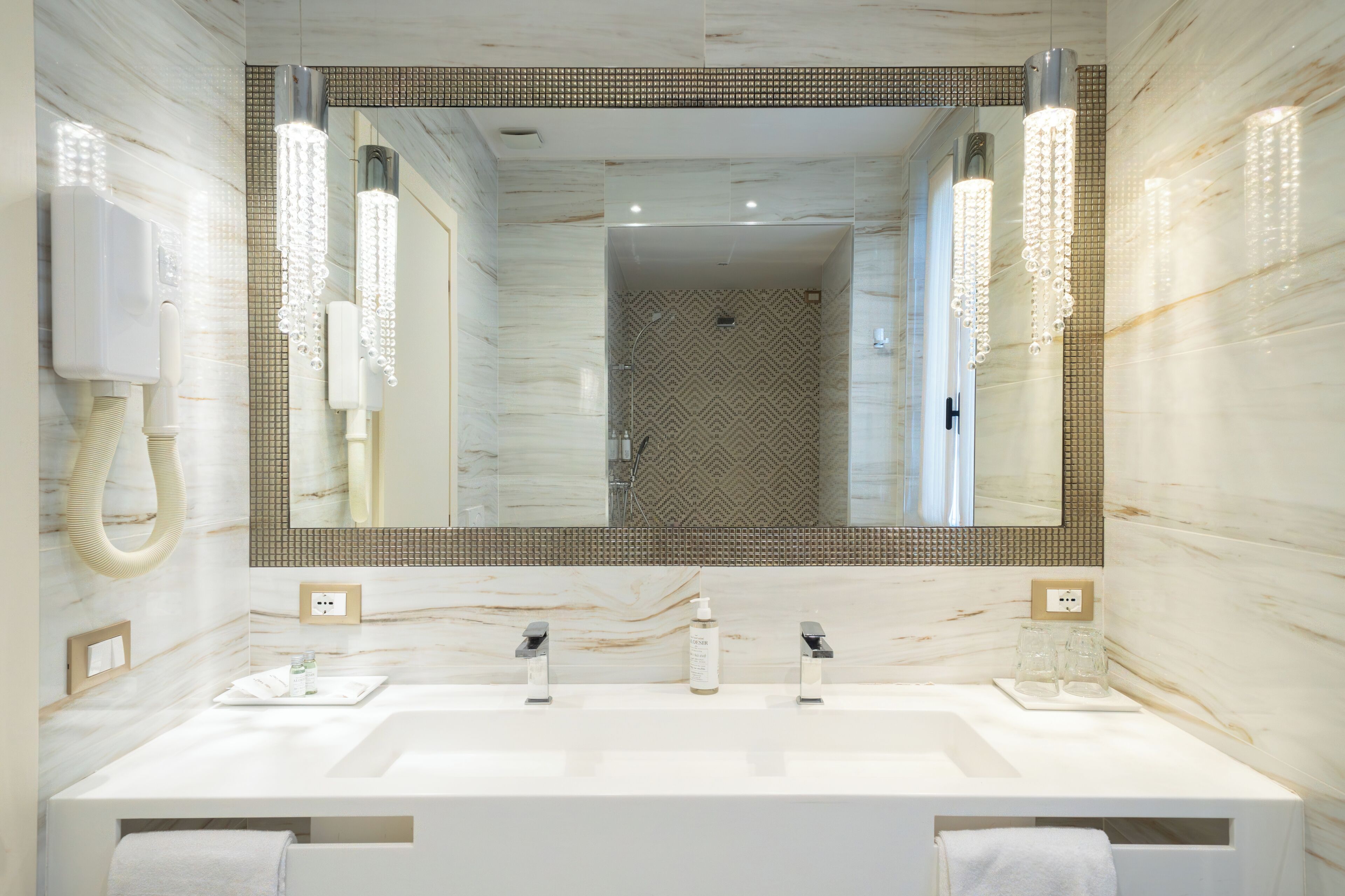 A bathroom with a large mirror, two sinks, a towel rack, and a shower area.