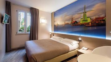 A hotel room with a bed, bedside table, and a large window.