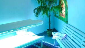A room with a massage table, a bench, a potted plant, and a stained glass window. - Panoramahotel Post (Bressanone)