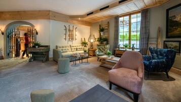 A cozy living room with a large window, a sofa, a chair, and a small table.