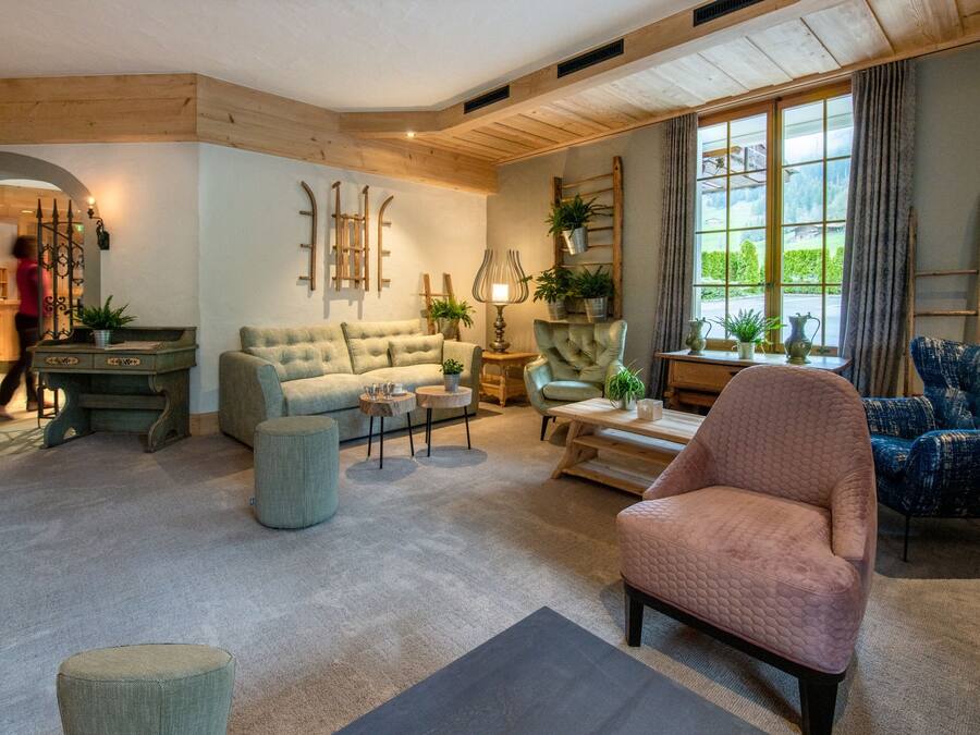 A cozy living room with a large window, a sofa, a chair, and a small table.