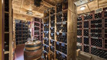 A wine cellar with wooden shelves and barrels, filled with wine bottles and labels.