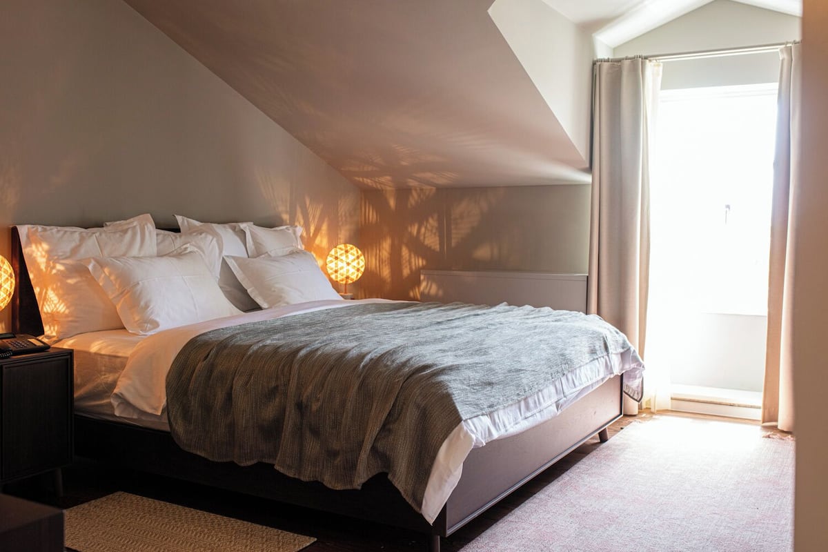 A bedroom with a bed, bedside tables, a lamp, and a window with curtains.