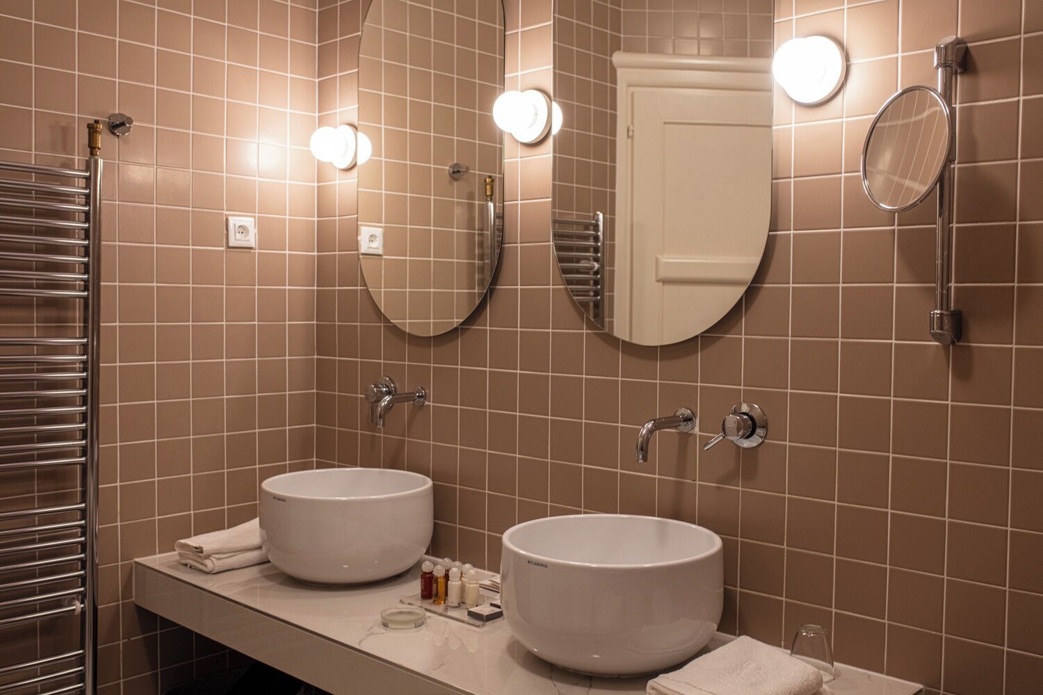 A bathroom with two sinks, a towel rack, a mirror, and a shower.
