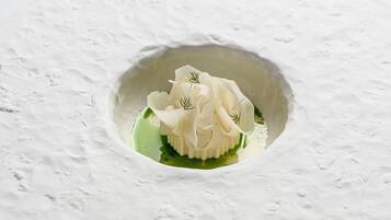 Un postre blanco en un bol con salsa verde y adorno de eneldo.