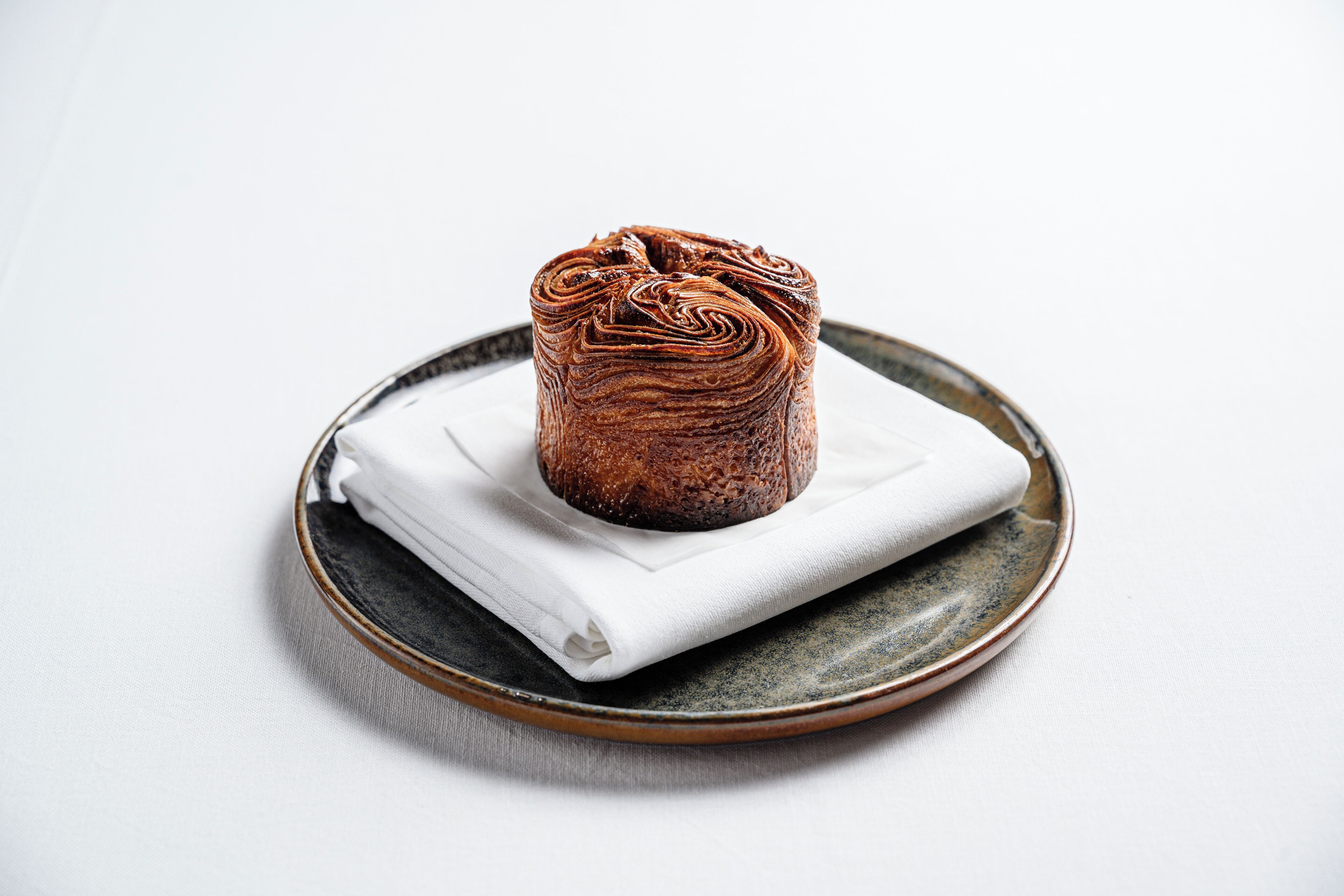 A loaf of bread on a ceramic plate with a napkin.