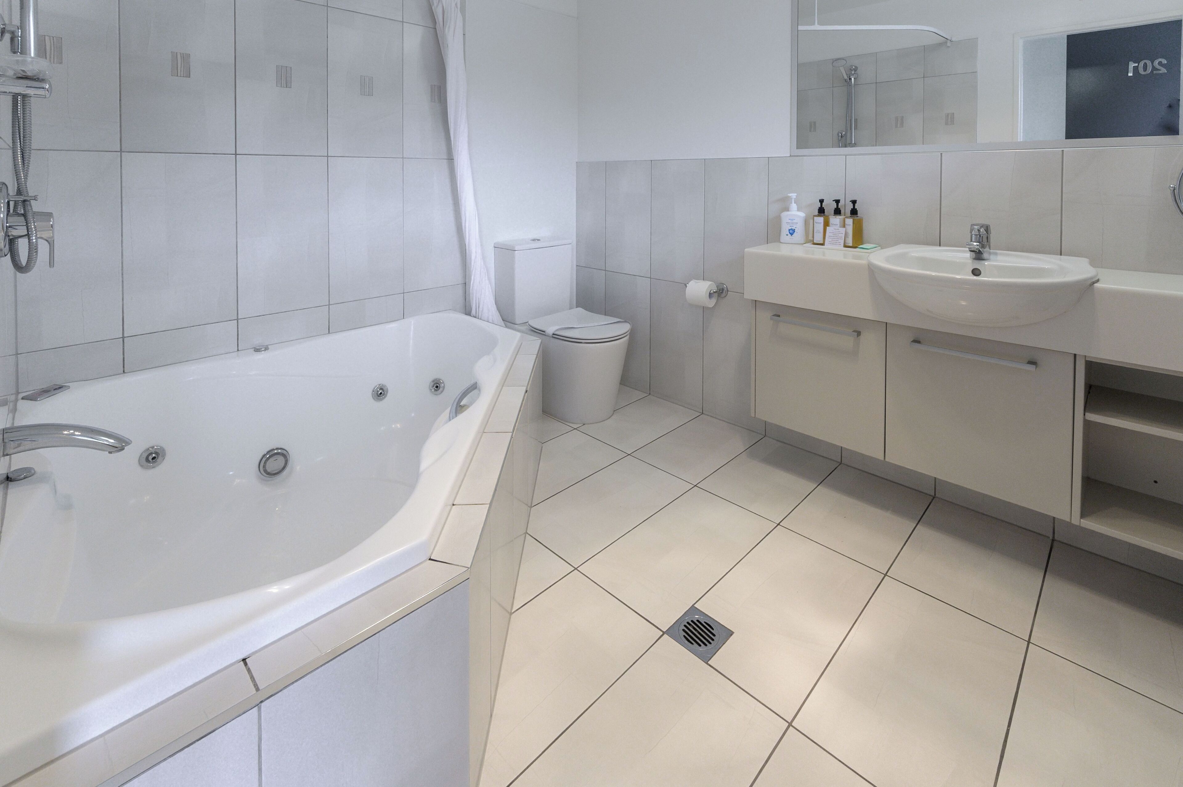 Un baño moderno con una bañera grande, un inodoro y un lavabo.