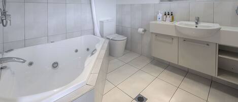Ein modernes Badezimmer mit einer großen Badewanne, einer Toilette und einem Waschbecken.