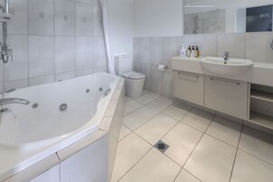 Un baño moderno con una bañera grande, un inodoro y un lavabo.