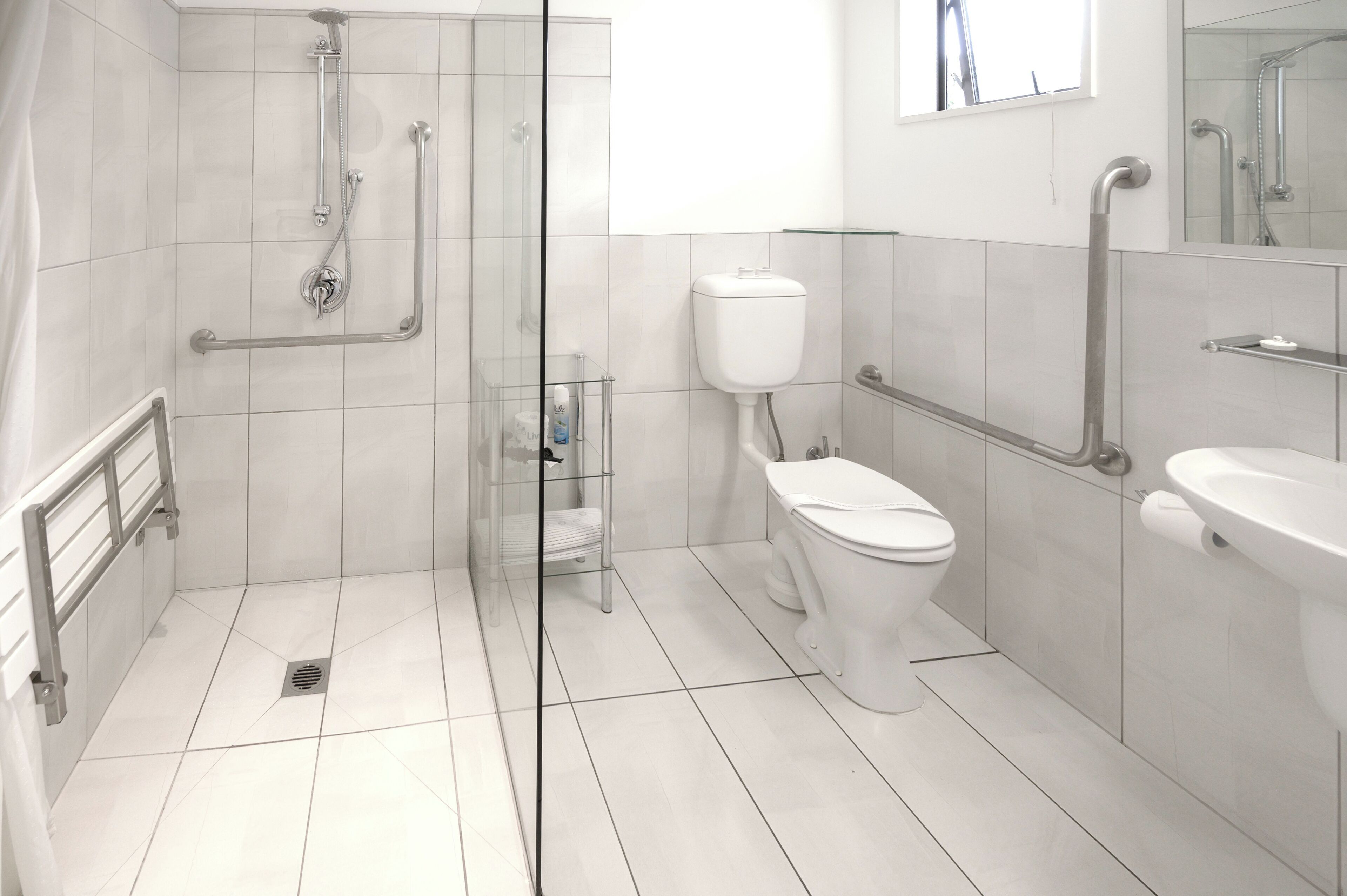 Een moderne badkamer met een douchecabine van glas, een toilet en een wastafel.
