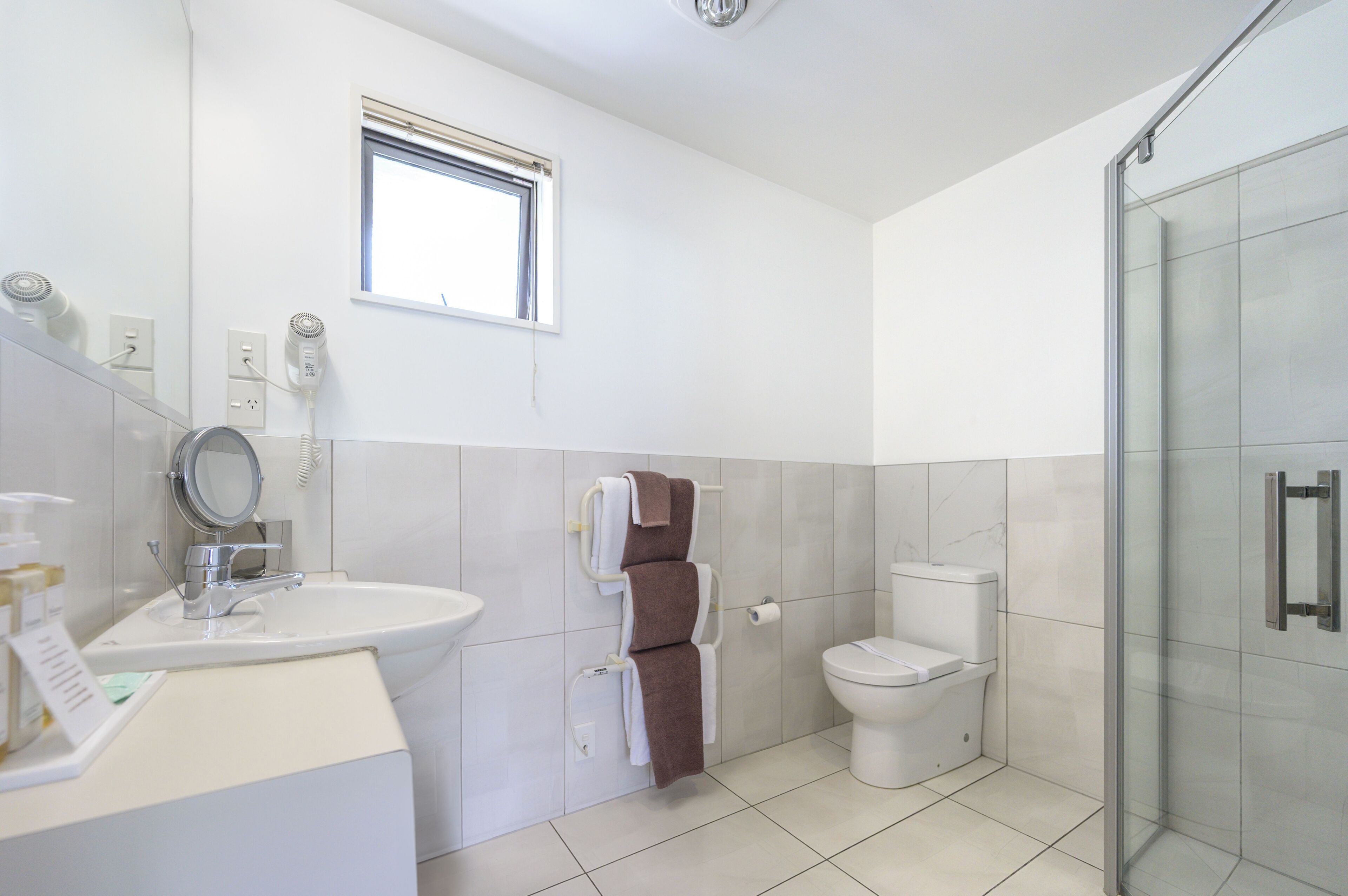 Un baño moderno con cabina de ducha de vidrio, un lavabo blanco y un inodoro.