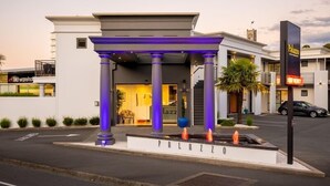 En hotellentrén med ett överbyggt område, en skylt med texten ”Palazzo” och en butik med namnet ”Lazz” som syns i bakgrunden.