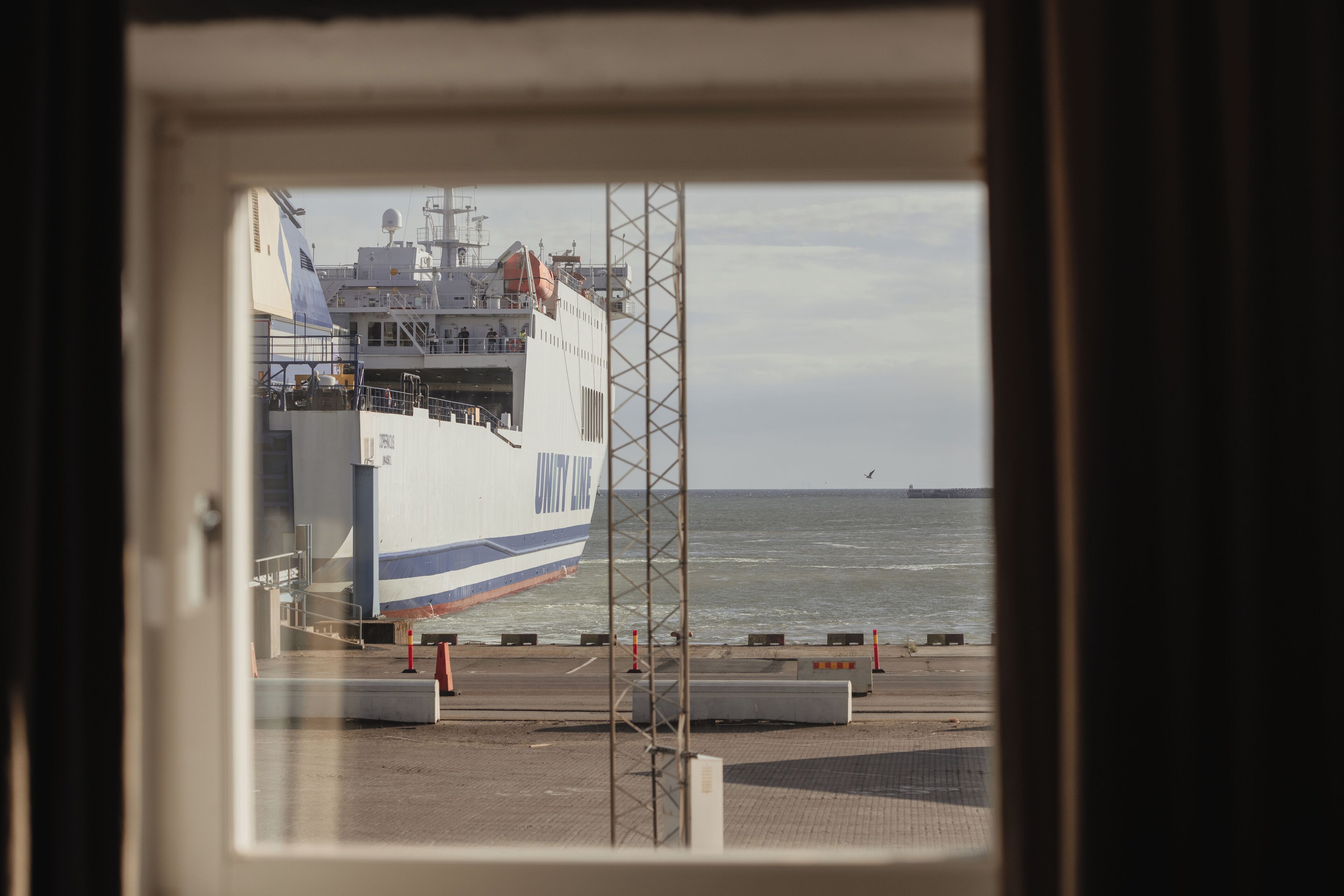 Blick auf ein Schiff, das in einem Hafen liegt, mit blauem Himmel und ruhiger See.