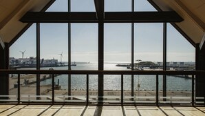 A view from a high window overlooking a harbor with ships, wind turbines, and industrial buildings. - Home Hotel Magasinet (Trelleborg)