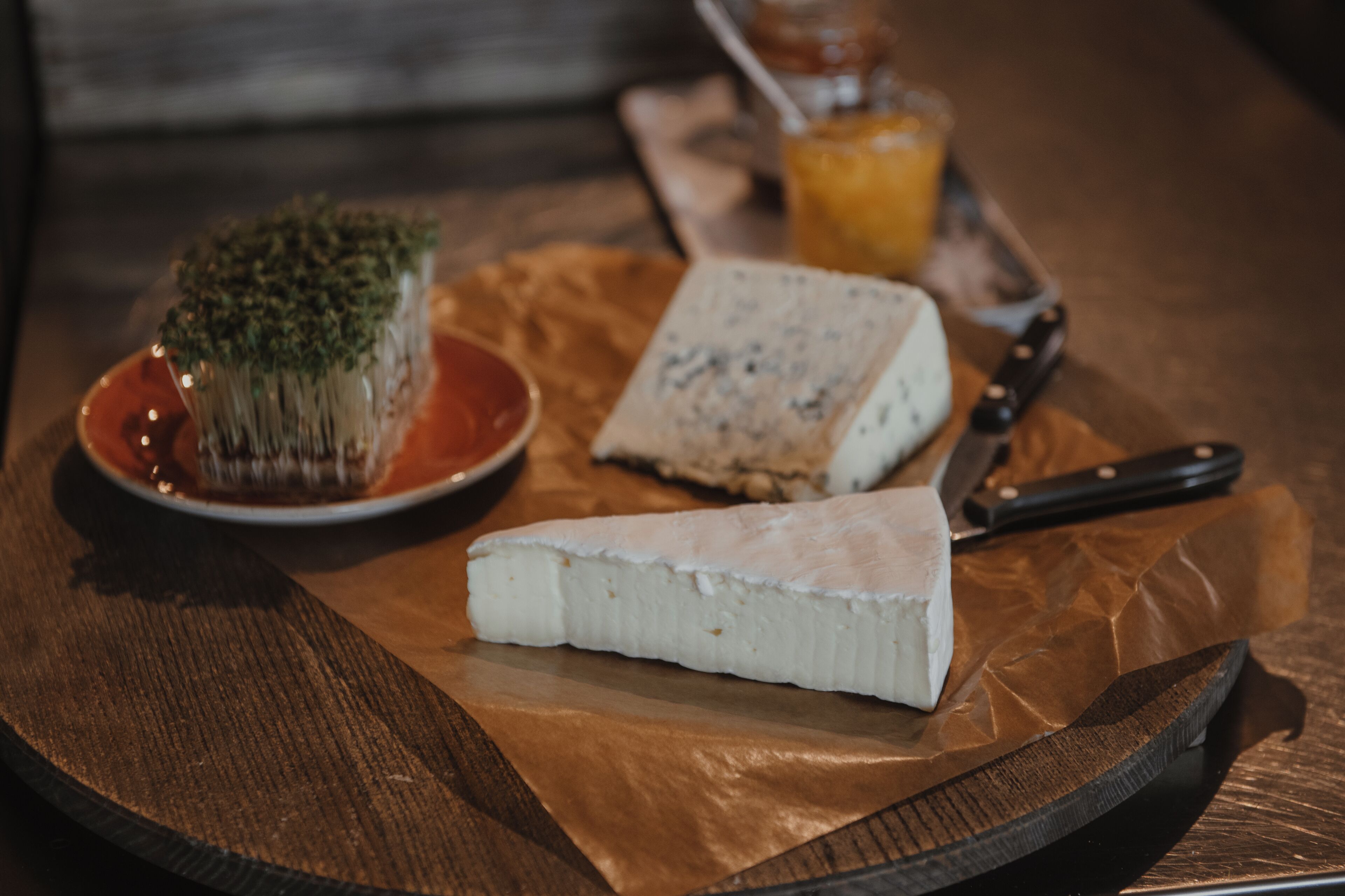 A cheese platter with various cheeses and a knife on a wooden table.