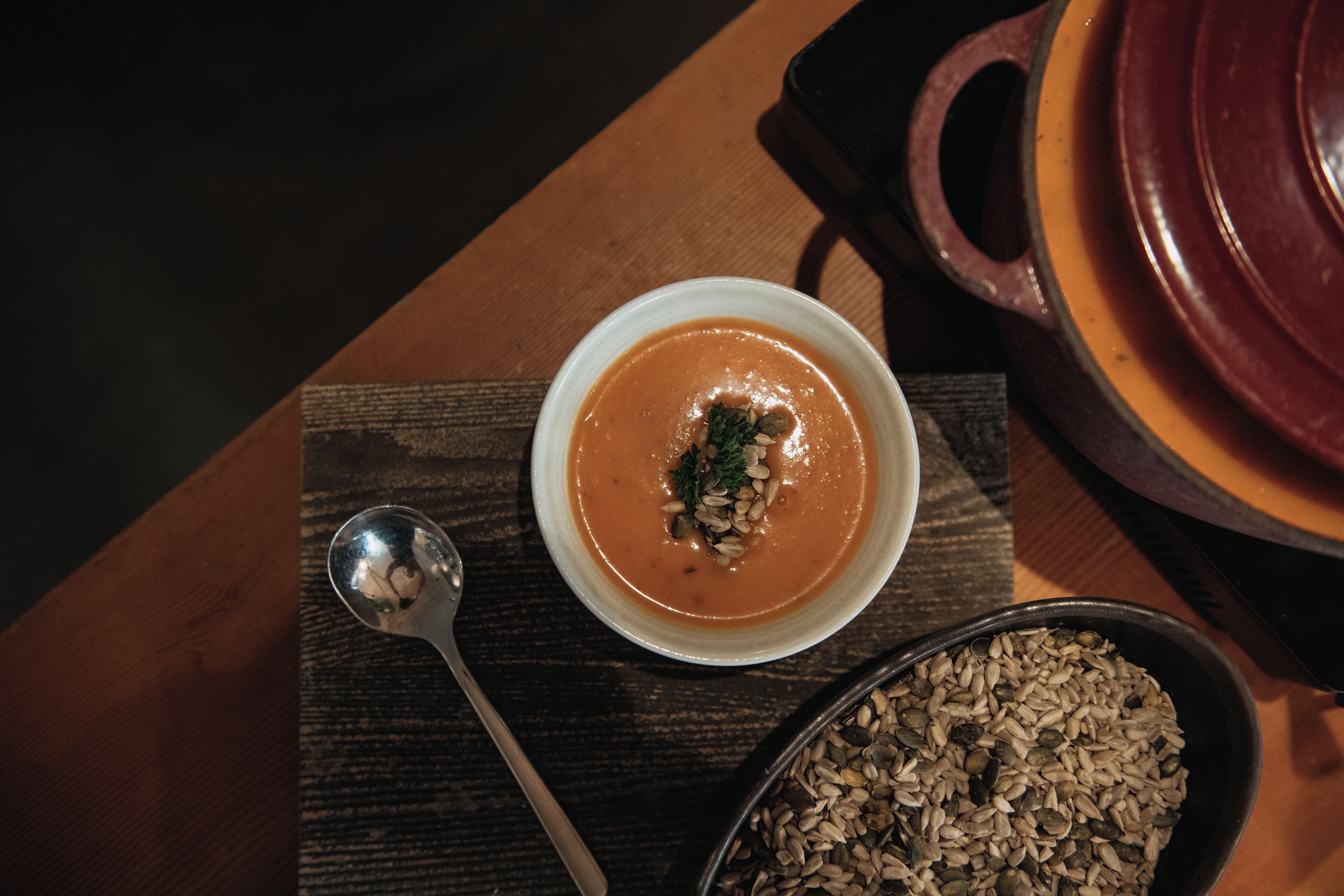 Un tazón de sopa con semillas sobre una mesa de madera.