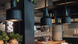 A kitchen with wooden countertops, hanging plants, and black pendant lights. - Home Hotel Magasinet (Trelleborg)