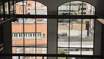 Vista a través de una ventana con un edificio de ladrillo y un coche rojo al frente.