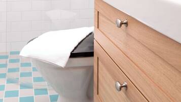 A bathroom with a white toilet, a wooden cabinet with drawers, and a checkered floor.