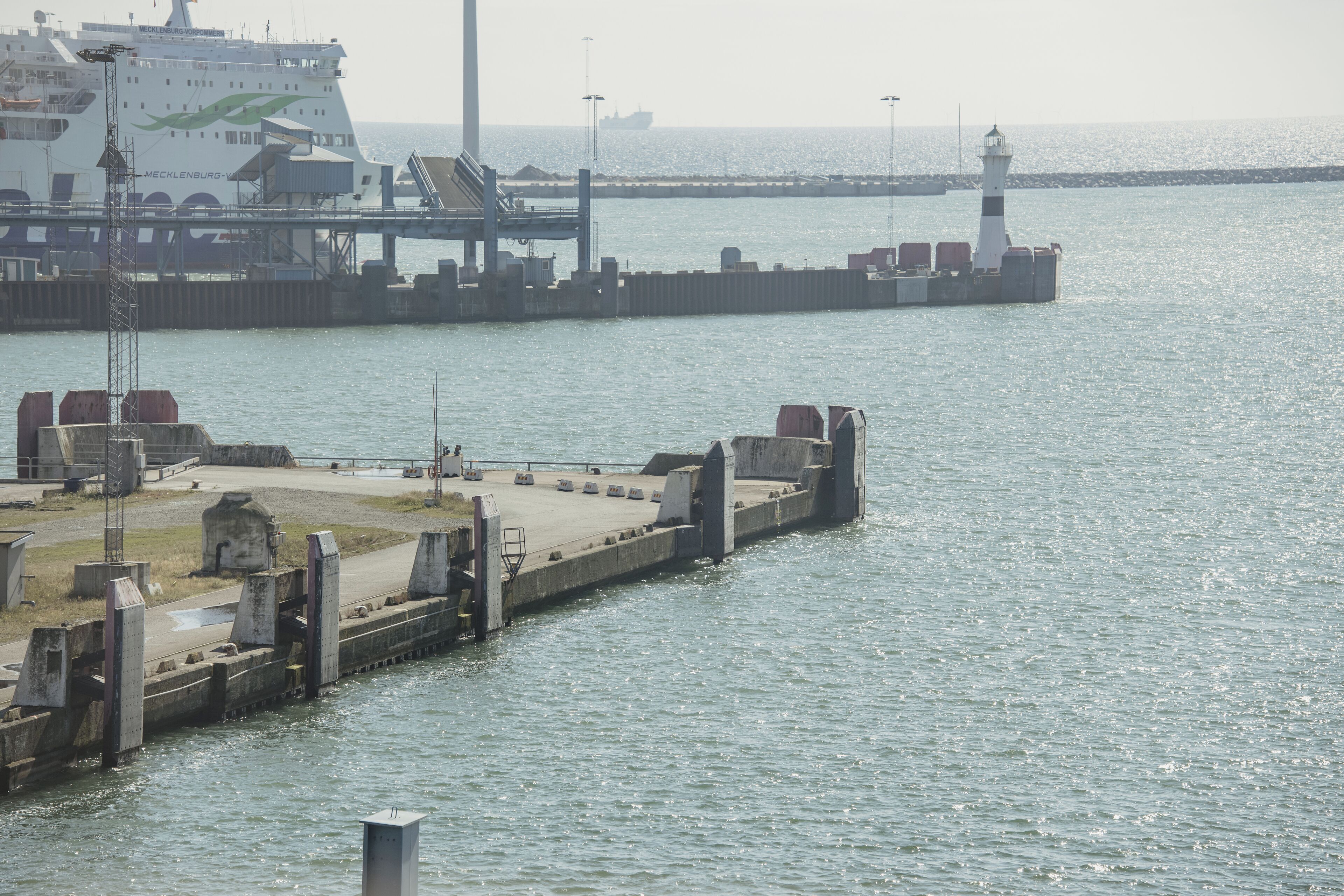 A pier with a lighthouse and a large ship docked.
