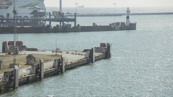 A pier with a lighthouse and a large ship docked.