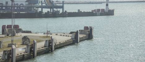 Un muelle con un faro y un gran barco amarrado.